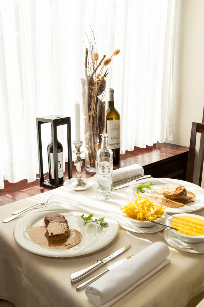 Gedeckter Tisch mit Rindsfilet und Entrecôte, Pommes und Risotto — Grotto Reale Zürich